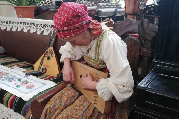 на фото специалист играет на балалайке