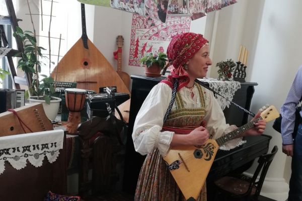 на фото ведущая играет на балалайке